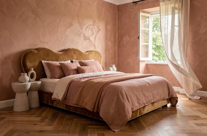 Chambre contemporaine avec tête de lit en velvet caramel, linge de lit en lin rose poudré et murs en stuc terracotta pour une décoration intérieure tendance