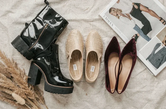 Flat lay de trois paires de chaussures tendance dont des bottines plateformes, des espadrilles et des ballerines en velours sur fond de lin crème